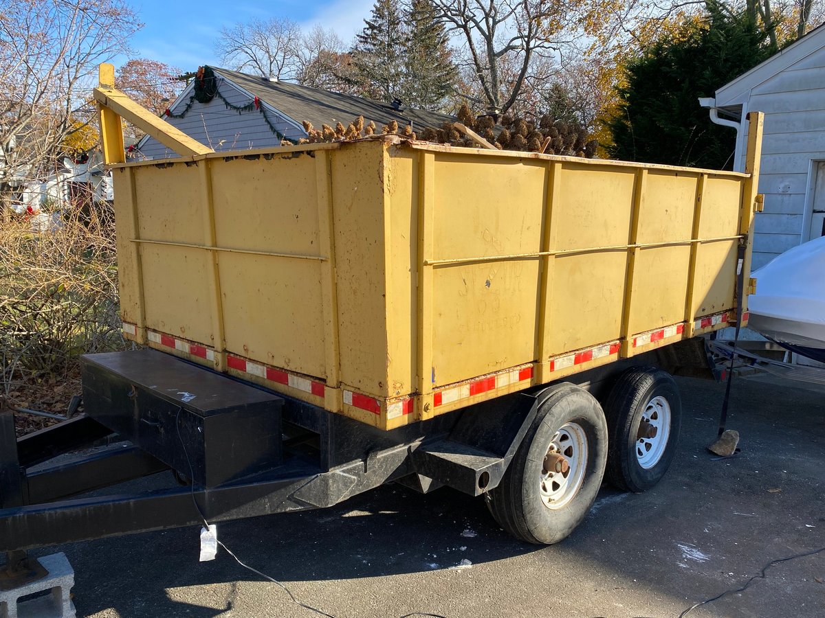 A portable dumpster trailer in a residential driveway