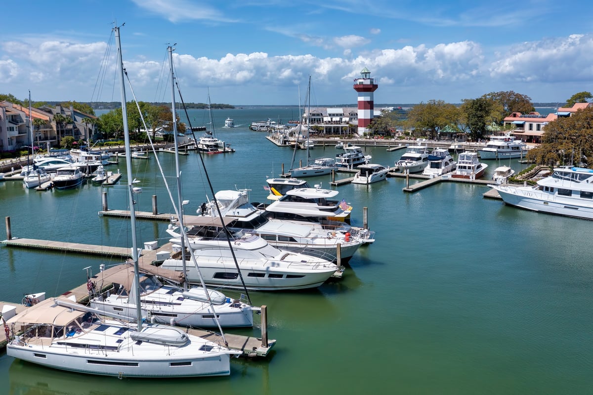 Aerial view of marina with boats and lighthouse in coastal community